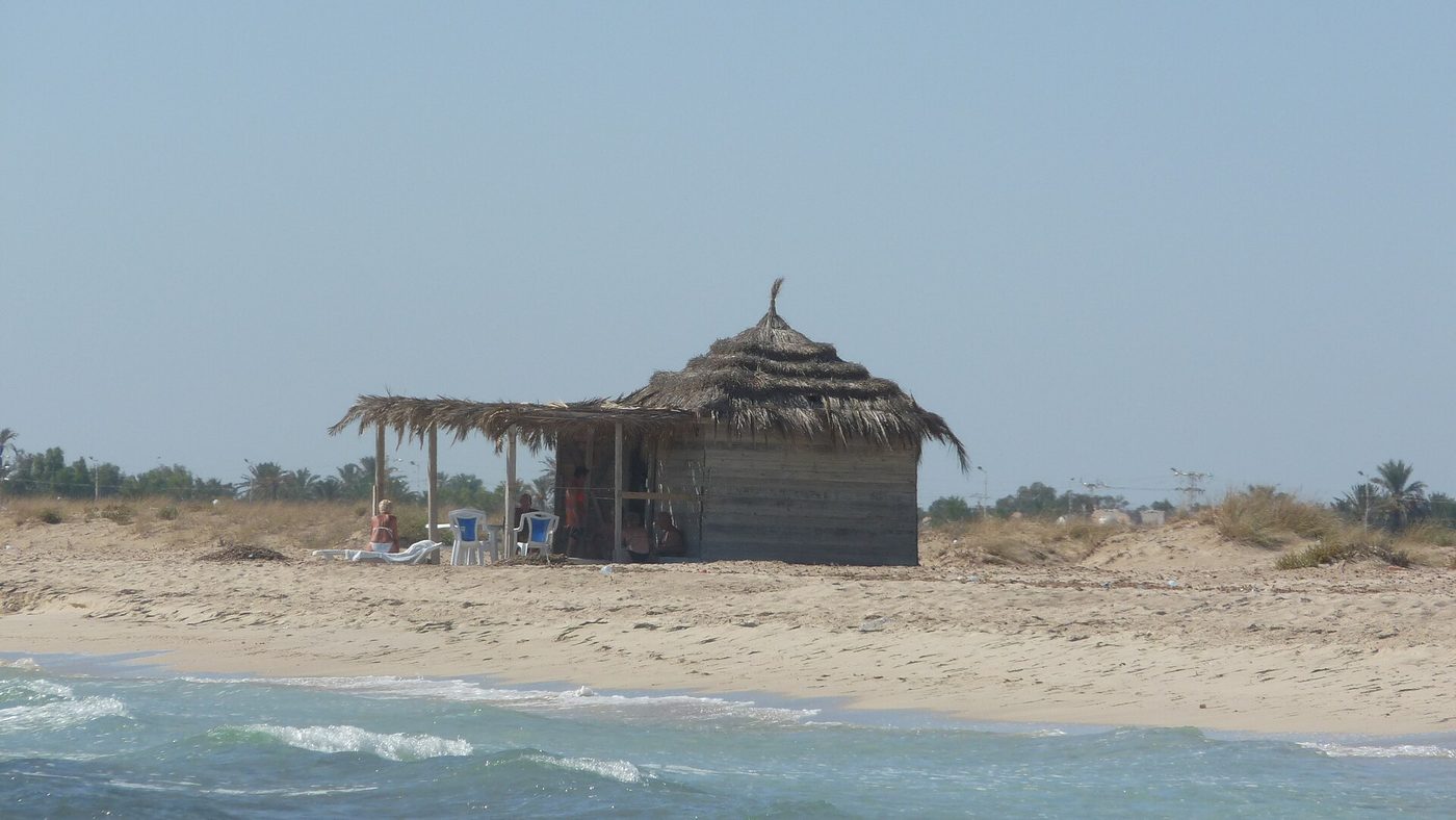 The long soft-sand hotel-zone strand of Sidi Mahrez beach on Djerba, Tunisia, with shallow turquoise sea