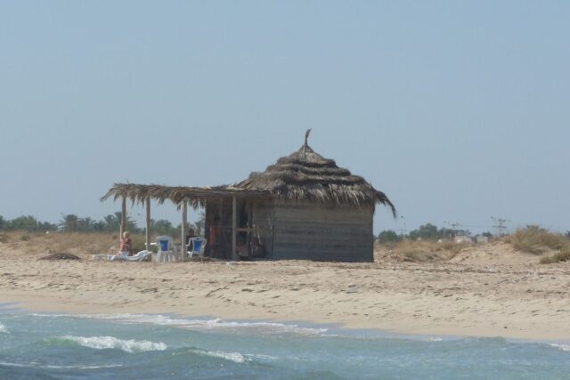 The pale sand and calm shallow sea of a Sidi Mahres beach on the island of Djerba, Tunisia's warmest coast
