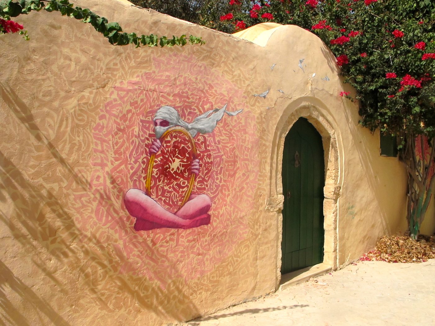 A quiet whitewashed lane in Erriadh village on Djerba, dotted with Djerbahood street-art murals