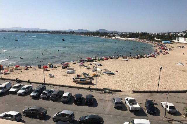 The soft pale sand of Hammamet's town beach with the honey-coloured kasbah and whitewashed medina rising over the water