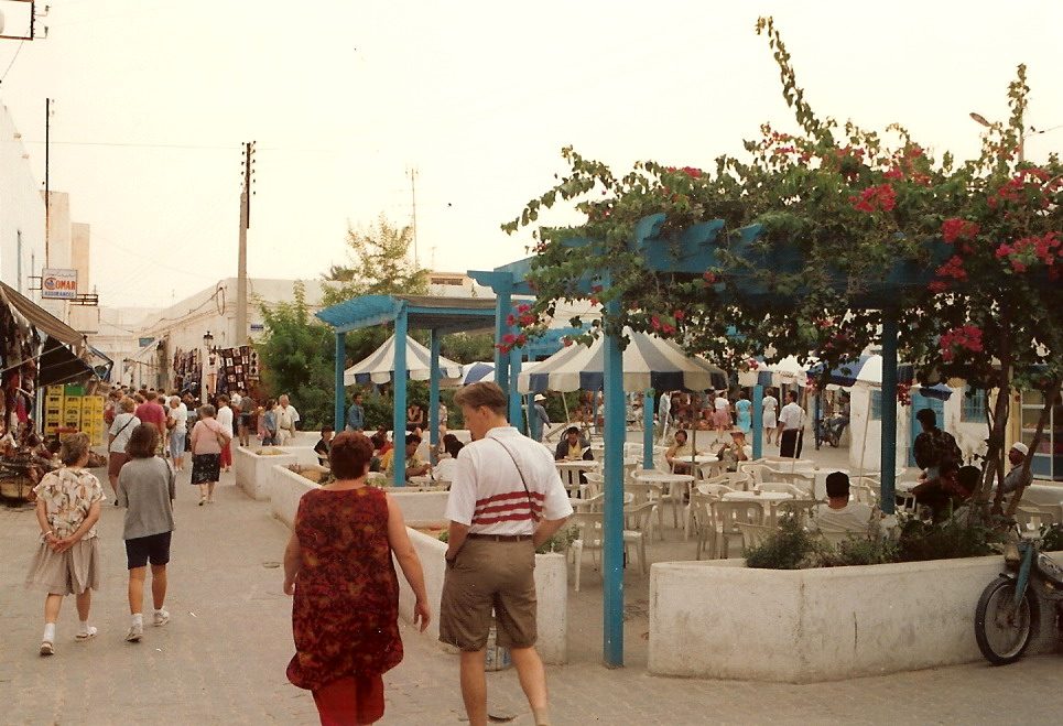 A traditional fondouk courtyard in Houmt Souk with arched galleries and blue doors, now a cafe