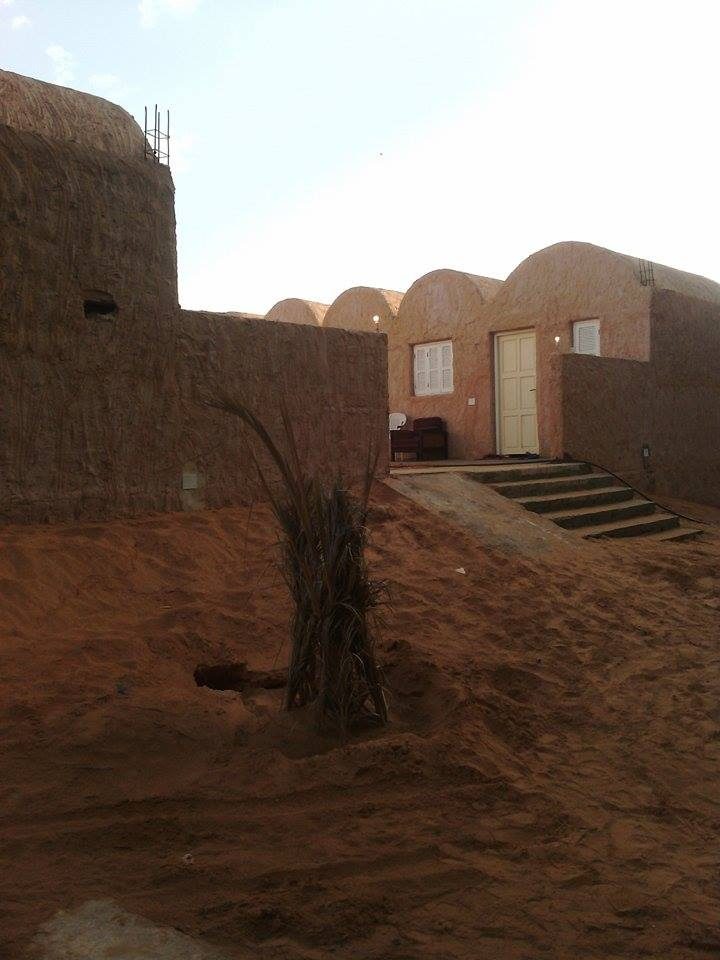 Mud-brick huts at the Ksar Ghilane oasis camp, beside the warm spring