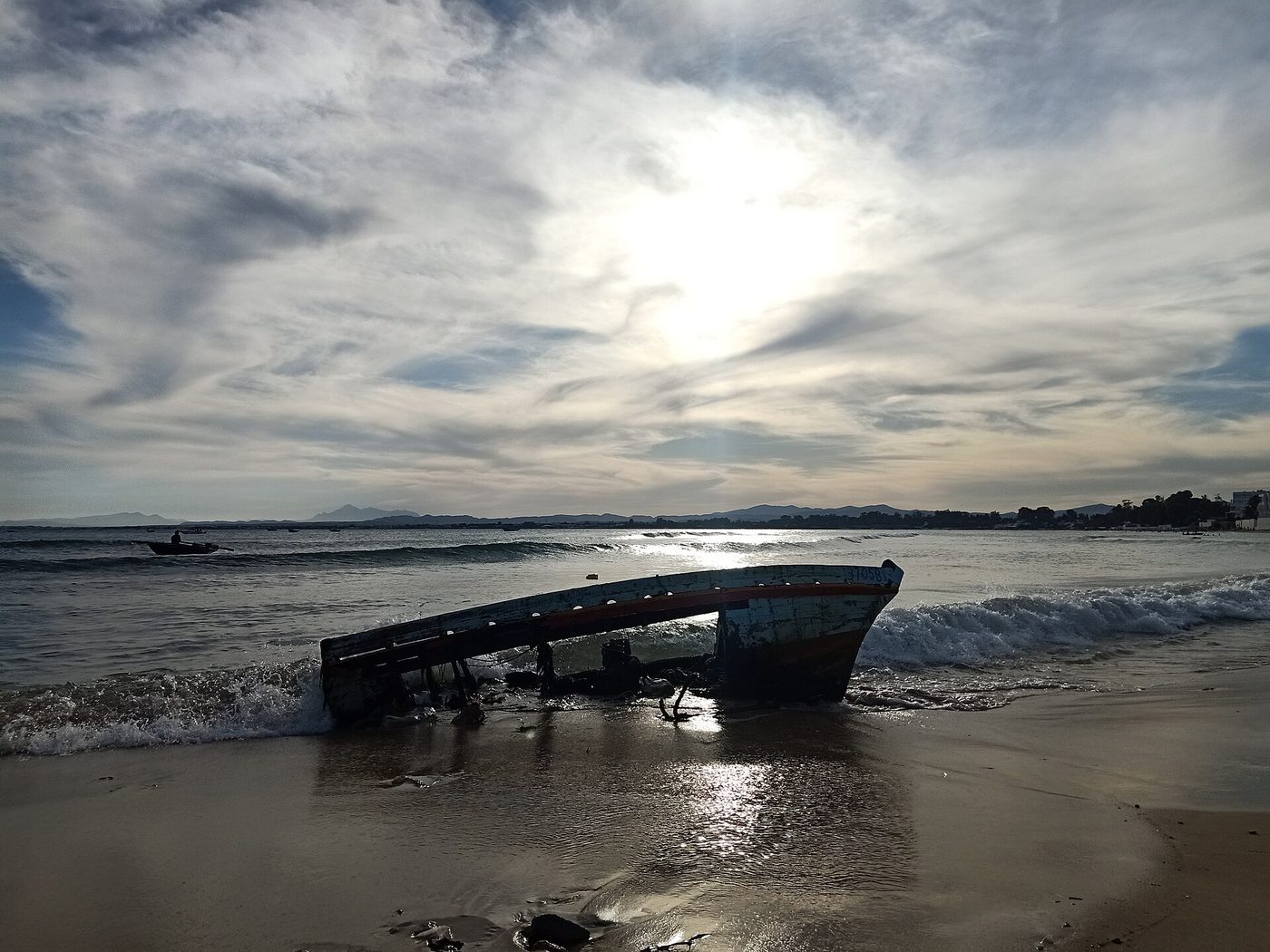 A wooden boat pulled up on the beach at Hammamet at sunset